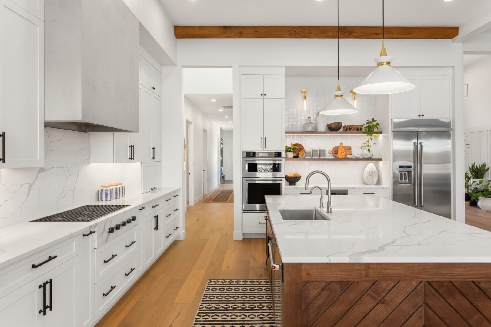 A kitchen with white cabinets and wood floors.